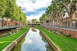 a canal in a city with buildings and trees at L'Authentique Centre-Ville - Perpignan in Perpignan