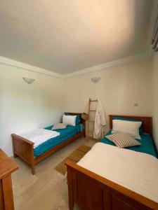 a room with two beds and a table at Azul Blue House in Sidi Bouzid