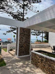 a pavilion with a stone wall and a tree at Azul Blue House in Sidi Bouzid