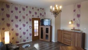a living room with a tv and flowers on the wall at Ferienwohnung Baars in Bad Sachsa