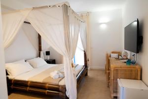 a bedroom with a canopy bed and a tv at Didimos Resort in Reggio di Calabria +36 photos