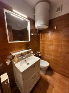 a bathroom with a sink and a toilet and a mirror at Montecampione Prati B in Pian Camuno
