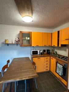 a kitchen with a wooden table and yellow cabinets at Montecampione Prati B in Pian Camuno +5 photos