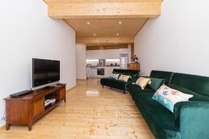 a living room with a green couch and a flat screen tv at Apartamento espaçoso em Lagos – ideal para grupos in Lagos