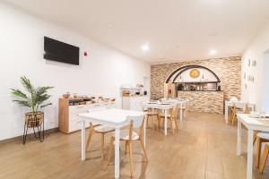 a restaurant with white tables and chairs and a kitchen at Vila Rosario in Ponta Delgada
