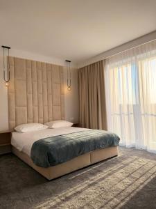 a bedroom with a large bed with a large window at Baltic Waves Ex LAZUR in Gąski