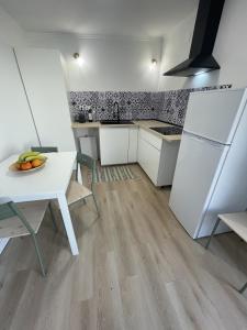 a white kitchen with a table and a white refrigerator at The Lemon Tree Villa in Charneca +9 photos
