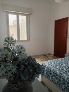 a bedroom with a vase with flowers on a table at Maison d'Artiste Siracusa Belvedere in Belvedere