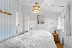 a white bedroom with a large bed and a chandelier at FAN026-Fano-Hedesvinget-12 in Fanø