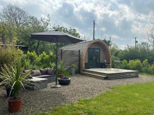 a small cabin with an umbrella in a yard at Glamping pod with en-suite & underfloor heating in Haverfordwest