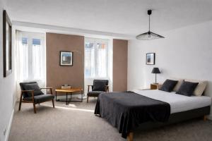 a bedroom with a bed and two chairs and a table at Flor du Mont Gîte in Pontorson