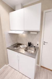 a small kitchen with a sink and white cabinets at Liten studioleilighet meget sentralt i sentrum, 3 minutter fra torget in Trondheim +45 photos
