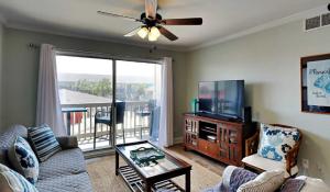 a living room with a couch and a tv at Vibrant gulf condo with pool and beach access in Pensacola Beach
