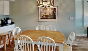 a dining room table with white chairs and a chandelier at Vibrant gulf condo with pool and beach access in Pensacola Beach +7 photos