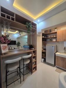 a kitchen with a bar with two stools and a refrigerator at Kai's Luxe Balcony Suite at Royal Oceancrest Mactan in Mactan Island