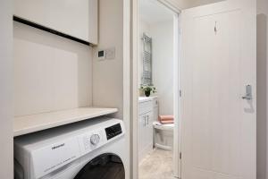 a white laundry room with a washing machine in it at Edegely House in Stockport
