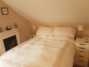 a bed with white sheets and pillows in a bedroom at Lammas Park House in Dawlish