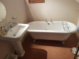 a white bath tub next to a sink in a bathroom at Lammas Park House in Dawlish