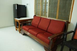 a red couch sitting in a room with a table at Green Heavan Farm in Sadras