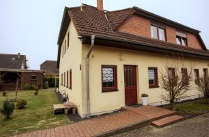 a white house with a red door and a yard at Zum Käutzchen 120qm Ferienhaus 8 Personen 4 Schlafzimmer in Nossentiner Hütte