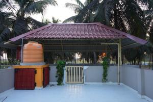 a gazebo with a gate and palm trees at Green Heavan Farm in Sadras