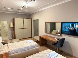 a room with two beds and a desk and a tv at Agora ApartHotel in Tirana