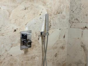 a shower in a bathroom with a stone wall at Agora ApartHotel in Tirana