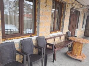 a group of chairs and a wooden bench on a porch at Hotel kazbegi1 in Ach'khoti