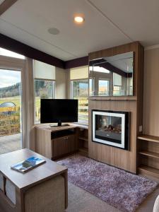 a living room with a tv and a fireplace at Bordeaux sea view no 9 in Ardentinny