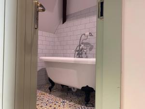 a white tub in a bathroom with pink tiles at The Bear Tattenhall in Tattenhall