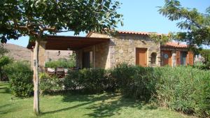 una piccola casa in pietra con un albero di fronte di Caviro on the Beach a Moúdhros