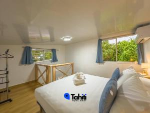 a bedroom with a bed with blue curtains at Moorea Temae Surf Tiny House in Teavaro