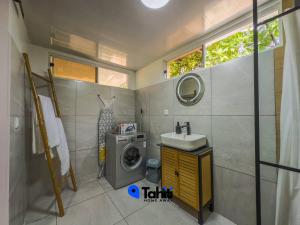 a bathroom with a washing machine and a sink at Moorea Temae Surf Tiny House in Teavaro