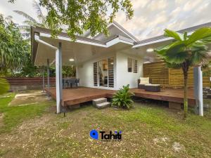 a house with a wooden deck in a yard at Moorea Temae Surf Tiny House in Teavaro