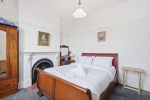 a bedroom with a bed with white sheets and a fireplace at Charming Sandy Bay Cottage in Sandy Bay