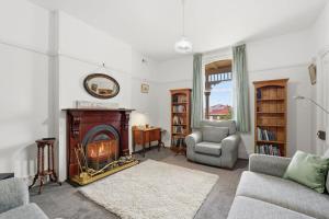 a living room with a fireplace and a couch and a chair at Charming Sandy Bay Cottage in Sandy Bay