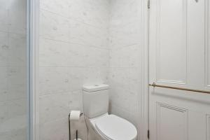 a white bathroom with a toilet and a door at Charming Sandy Bay Cottage in Sandy Bay +17 photos