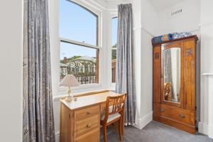 a desk in a room with a window and a dresser at Charming Sandy Bay Cottage in Sandy Bay