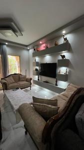 a living room with a couch and a tv on a wall at Spring house in Qaryat Shākūsh