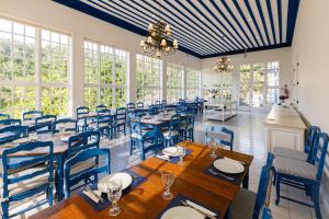 a dining room with blue chairs and tables and windows at Fazenda Santanna Hotel in Amparo