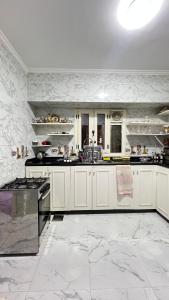 a large kitchen with white cabinets and black appliances at Spring house in Qaryat Shākūsh