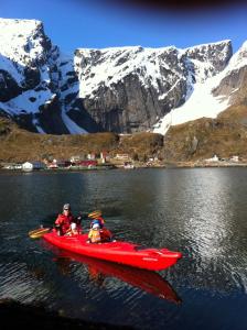 two people in a red kayak on a lake with mountains at Lofoten Bed & Breakfast Reine - Rooms & Apartments in Reine