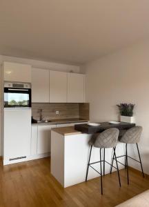 a kitchen with white cabinets and a table and chairs at Pipanova Cosy Nest with Balcony & Free Parking in Ljubljana