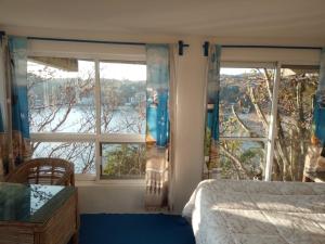 a bedroom with a bed and two windows with a view at The Blue Apartment in Puerto Ángel