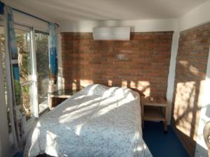 a bedroom with a bed and a brick wall at The Blue Apartment in Puerto Ángel