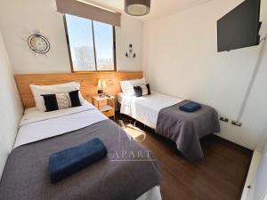 two beds in a room with a flat screen tv at NORTHSUITE - Vista al Mar - 3 Dormitorios - Parking in Antofagasta