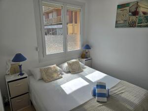 a bedroom with a large white bed with a window at Le 18 plage in Valras-Plage