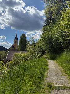 a dirt road with a church in the background with a tree at Appartement Luisa in Bad Kleinkirchheim +21 photos