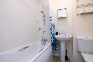 a bathroom with a tub and a sink and a toilet at Fantastic 4 bed house with 3 bathrooms in pleasant location in Great Barr +11 photos
