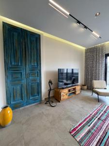 a living room with a tv and a blue door at Charming privado in Madinaty